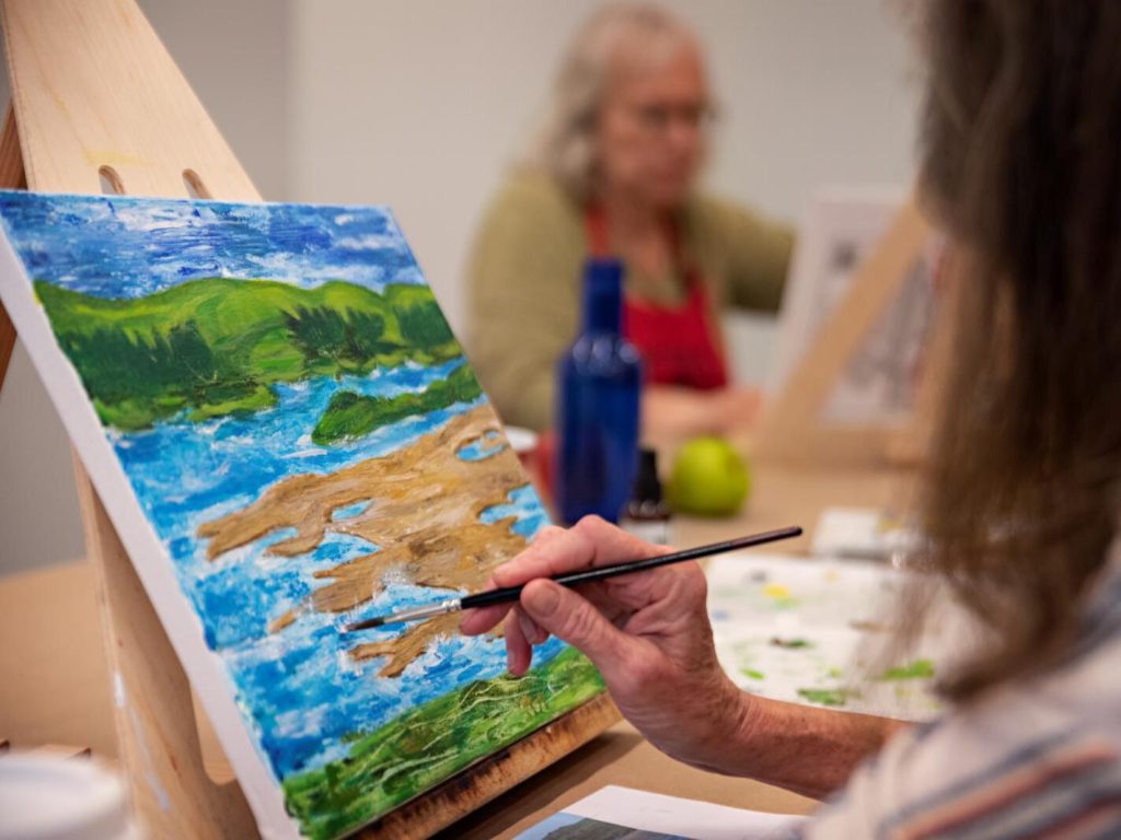 Adult student paints landscape from table top easel (SAC)-Escola pintura «Mediterrania»